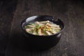 Paste of rice flour with scallion, coriander, deep fried garlic and porks on top in black porcelain bowl Royalty Free Stock Photo