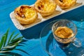 Pasteis de nada and an glassy espresso cup on deep blue wooden boards. a fern twig is on the right edge Royalty Free Stock Photo