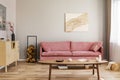 Pastel abstract painting on beige wall behind velvet pink settee in simple living room Royalty Free Stock Photo