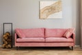 Pastel abstract painting on beige wall behind velvet pink settee in simple living room Royalty Free Stock Photo