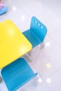 Pastel blue and yellow wooden child Table and Chairs on white tile floor in Kindergarten Preschool Classroom Royalty Free Stock Photo