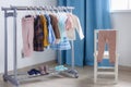 Pastel color children`s clothes in a Row on Open Hanger indoors. Clothes for little ladies hung in the children`s room Royalty Free Stock Photo