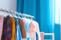 Pastel color children`s clothes in a Row on Open Hanger indoors. Clothes for little ladies hung in the children`s room