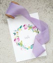 Pastel color hand drawed postcard and silk lillac ribbon on concrete background