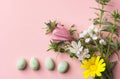 Pastel colored chocolate eggs bouquet of spring field flowers on light pink background with linen paper texture. Easter card