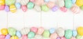 Easter banner with double border of pastel Easter Eggs over a white wood background with copy space