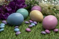 Pastel colored Easter eggs and pastel colored chocolate candy on green grass Royalty Free Stock Photo