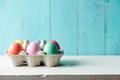 Pastel colored easter eggs in a egg box and turquoise background Royalty Free Stock Photo