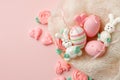 Pastel colored Easter eggs in nest, sweet tender decor from funny meringue and on pink background. Traditional springtime holiday