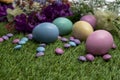 Pastel colored Easter eggs and pastel colored chocolate candy on green grass Royalty Free Stock Photo