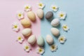 Pastel colored eggs arranged in a circle with white flowers on split pink and blue background, top view Easter spring composition, Royalty Free Stock Photo