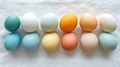 Pastel colored eggs arranged in two rows on white fabric Royalty Free Stock Photo