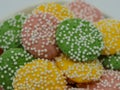 Pastel colored, green, yellow and pink white chocolate mint candies covered in white dot sprinkles piled up close