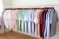 Pastel-colored shirts hanging on hangers against white wall in a cozy clothing store display Royalty Free Stock Photo