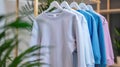 Pastel-colored sweatshirts on hangers with green plant background. Fashion and retail concept