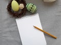 Pastel colors and decorated easter eggs, wreath and blank notebook with pencil on grey fabric background. Royalty Free Stock Photo