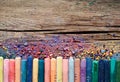 Pastel crayons and pigment dust on rustic wooden background.