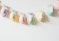 Pastel Easter egg garland with bunny ears and white feathers hanging on wall Royalty Free Stock Photo