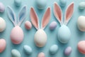 Pastel Easter eggs with bunny ears arranged on a blue background in a playful holiday pattern, Royalty Free Stock Photo