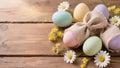 Pastel Easter eggs with burlap bunny wrapping and spring flowers on rustic wooden surface. Creative holiday table decoration Royalty Free Stock Photo