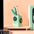 A pastel green desktop pen holder with tech inspired design on a soft peach backdrop