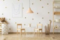 Pastel lamp above table between chairs in gold kid`s room interi Royalty Free Stock Photo