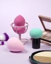 Pastel make-up tool included blender sponge brush powder brush on on purple background