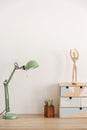 Pastel mint colored lamp on wooden desk with books, copy space on empty white wall