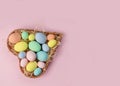 Pastel multi-colored Easter eggs in a basket in the shape of a heart on a pink background. Place for text. Greeting card Royalty Free Stock Photo