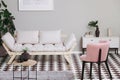 Pink armchair and beige scandinavian futon in trendy living room interior with black and white floor Royalty Free Stock Photo