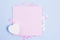 Pastel pink blank card mockup and white wooden heart on pastel blue background with scattered pink glitter stars. Place for your