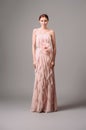 Pastel pink cocktail ruffled dress with fabric flower. Romantic festive evening look. Full-length elegant gown with high heels