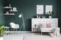 Pastel pink decorations in a scandi bedroom interior for a teenage girl with modern, white furniture and dark green walls Royalty Free Stock Photo