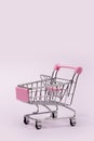 Pastel pink miniature shopping cart on pink background