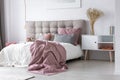 Pastel pink sheets on white duvet in stylish bedroom