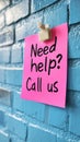Pastel Pink Sticky Note With Need Help Call Us Written, On Blue Brick Wall With Copyspace. Royalty Free Stock Photo