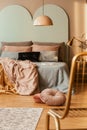 Pastel pink stylish lamp above comfortable bed with cozy bedding