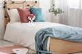 Velvet pastel pink and turquoise pillows and toy fox on single wooden bed with white bedding and blanket Royalty Free Stock Photo