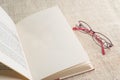 Pastel reading glasses with opened blank book on burlap sack Royalty Free Stock Photo