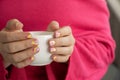 Pastel softness colorful manicured nails. Woman holding white cup of coffee or tea showing her new summer manicure in