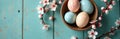 Pastel speckled Easter eggs sit in rustic bowl with white spring blossoms on teal table. Gentle overhead view conveys serene Royalty Free Stock Photo