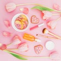 Pastel tulips flowers, cosmetics with aroma and sweet cookies on pink background. Flat lay, top view.