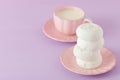Pastel violet horizontal banner with copy space - white zephyr dessert on pink plate and cup of coffee with milk.