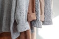 Pastel warm knitted clothes sweater hanging in the closet. Cozy autumn and winter wardrobe