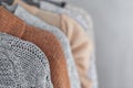 Pastel warm knitted clothes sweater hanging in the closet. Cozy autumn and winter wardrobe