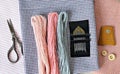 Pastel wool embroidery threads, needles, cotton fabric, retro scissors, wooden buttons and leather thimble Royalty Free Stock Photo