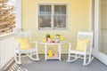 pastel yellow cape cod, porch with rocking chairs and lemonade setup Royalty Free Stock Photo