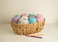 Pastell coloured woolen balls in a basket with crochet hooks for crocheting and handicraft