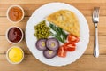 Pasties, vegetables, bowls with sauces and fork on wooden table. Royalty Free Stock Photo