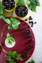 Pastila of black currant on a light background. A branch with green leaves nearby. Black currant berry in a ceramic bowl. Vertical Royalty Free Stock Photo